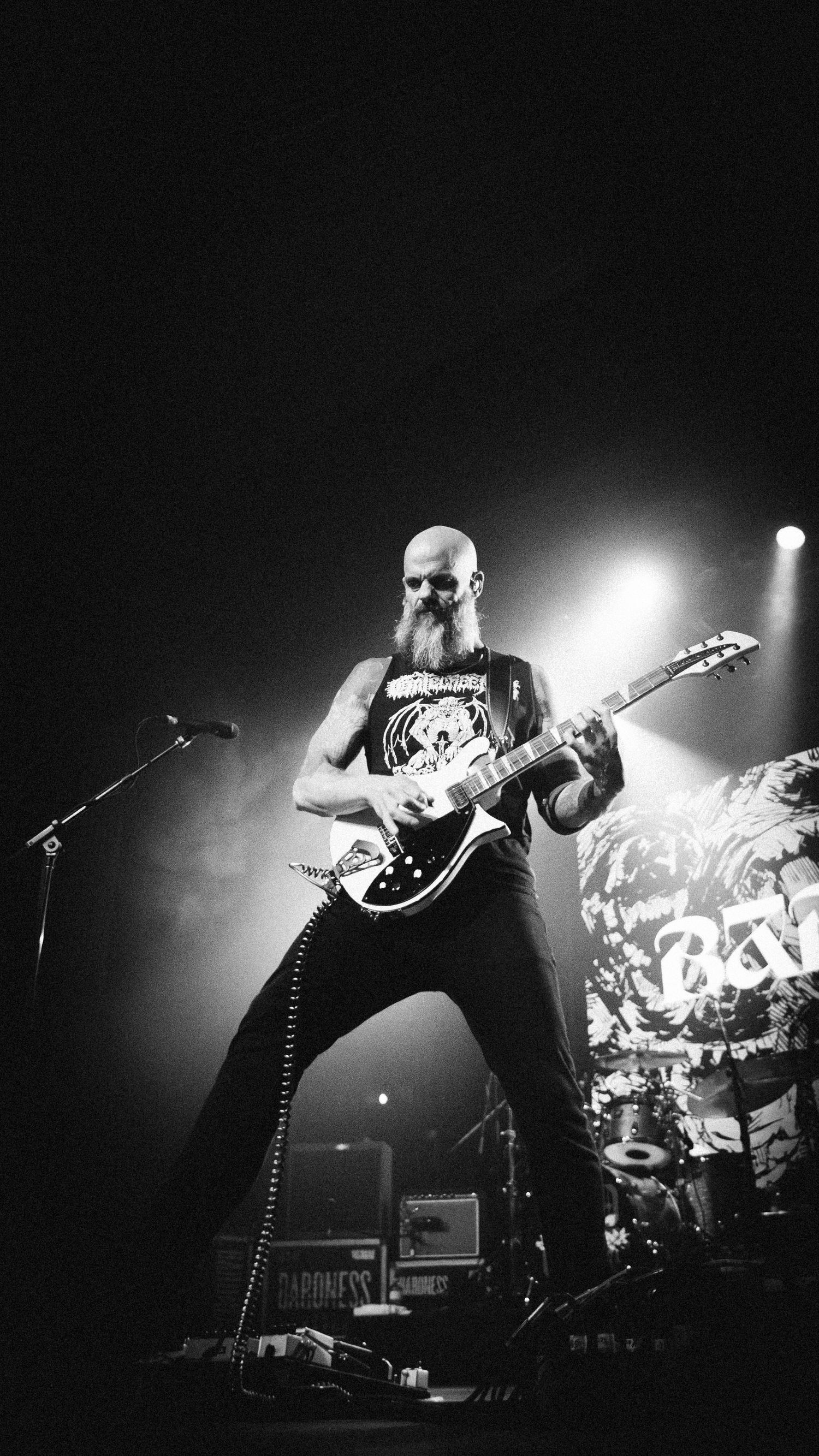 Bearded Baroness guitarist in a sleeveless shirt under a spotlight with his guitar, The Palace Theatre, Calgary