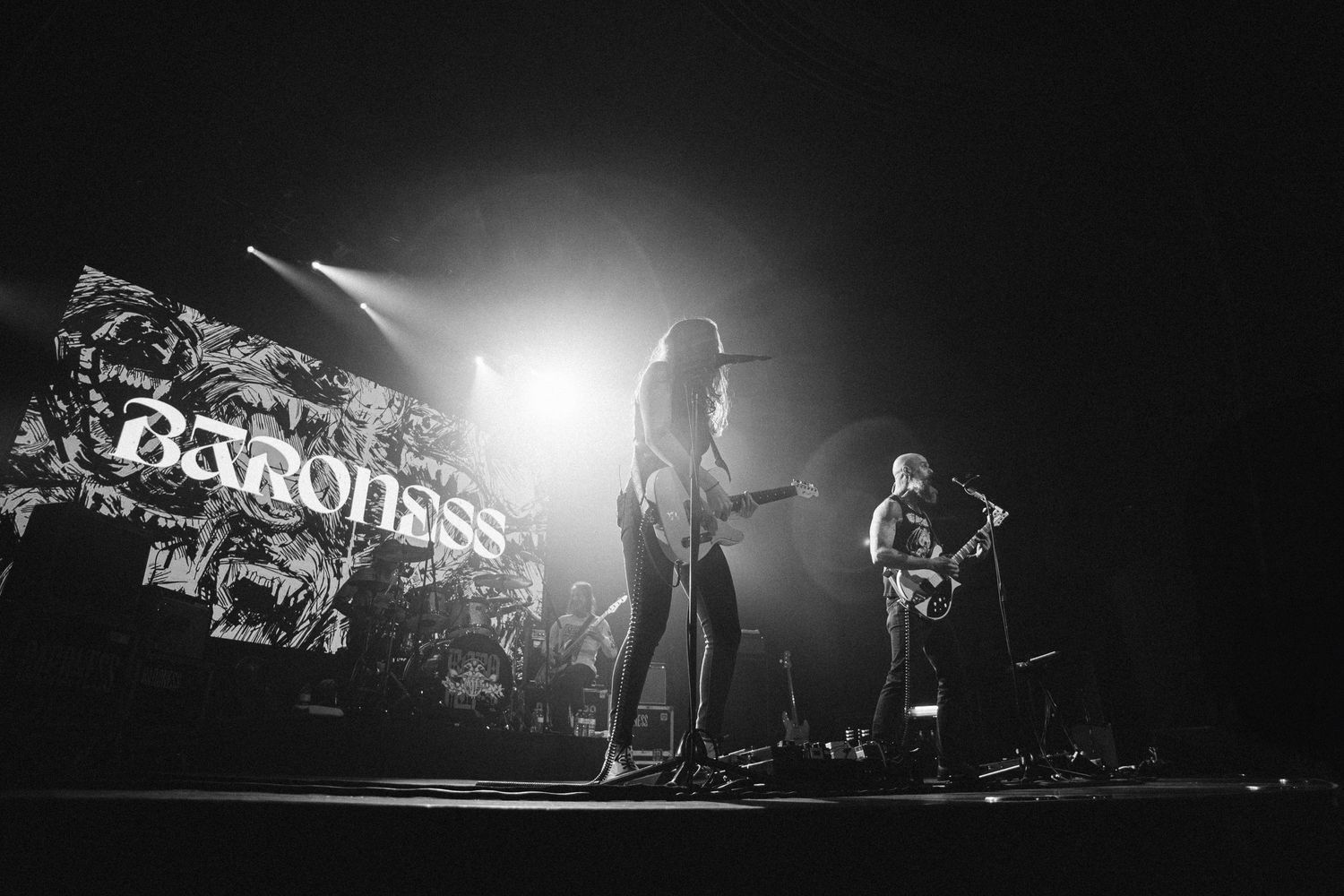 Two Baroness guitarists in near silhouette against bright backlight and the logo screen, The Palace Theatre, Calgary