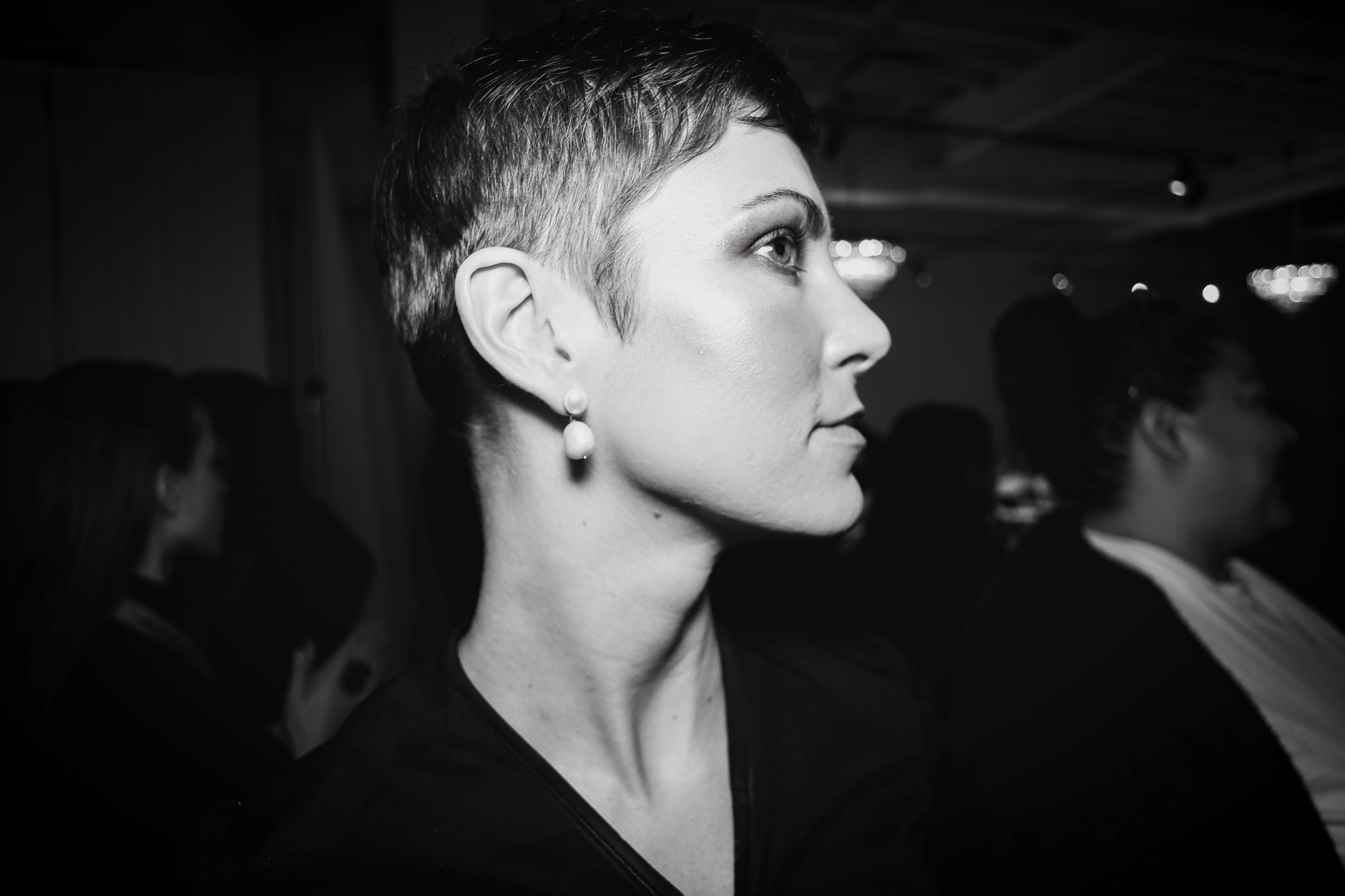 Black and white backstage profile of model Victoria with a short pixie cut and pearl earring, Edmonton Fashion Week 2024
