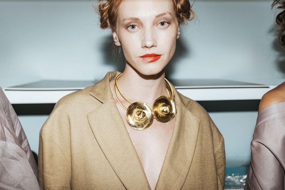 Backstage portrait of a red-haired model in a camel blazer and gold rose necklace at Mexico City Fashion Week