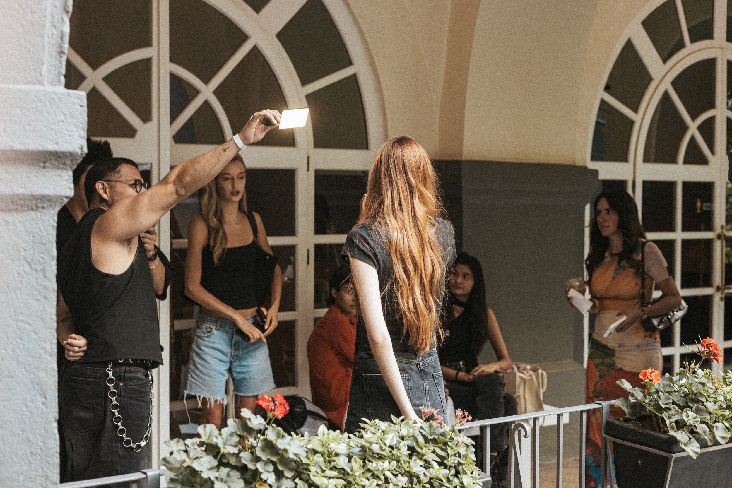 Crew member holds a reflector overhead as models wait by white arched windows at Mexico City Fashion Week