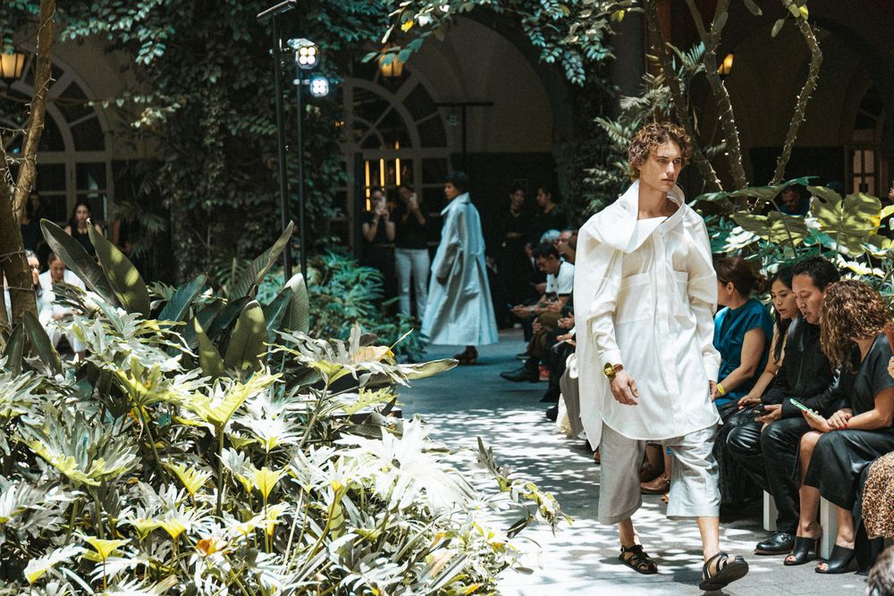 Model in an oversized white shirt, cropped trousers and sandals walks a leafy courtyard runway, Mexico City Fashion Week