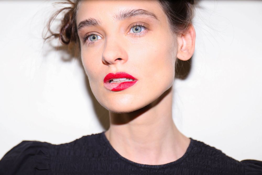 Close-up of a model with blue eyes, loose updo and bold red lipstick, backstage makeup by MAC at Mexico City Fashion Week