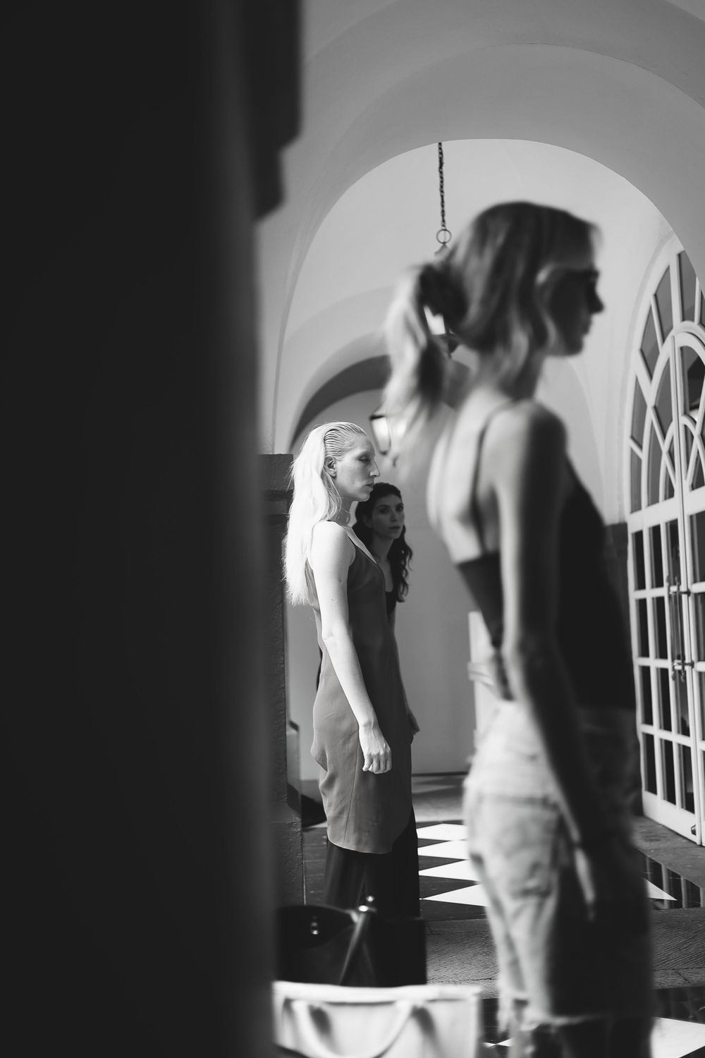 Black and white image of models lined up under an arched corridor backstage at Mexico City Fashion Week