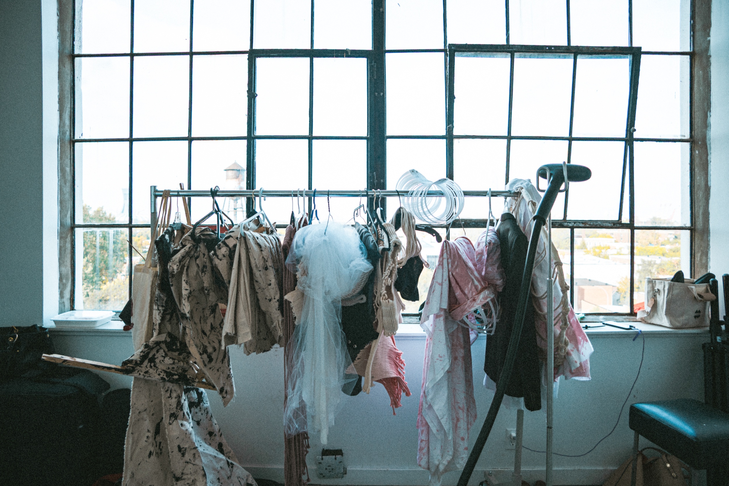 Clothing rack of lace, floral and sheer garments before a tall industrial window, Montreal Fashion Week 2025